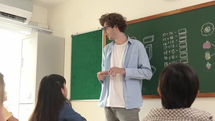 Professional mentor looking around classroom while standing in front of blackboard with math formula or theory. Diverse elementary student learning or studying and sitting in Math lesson. Pedagogy. - Powered by Adobe