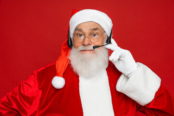 Photo of pensioner old man grey beard hold telephone raise direct finger smile listen kids wish wear x-mas costume leather belt gloves coat spectacles headwear isolated red color background