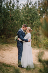 Couple embracing in a serene outdoor setting, surrounded by lush greenery, dressed in elegant wedding attire, capturing a moment of love and connection in nature's beauty