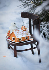 Gingerbread house and holiday decoration on chair in snow winter outdoor background