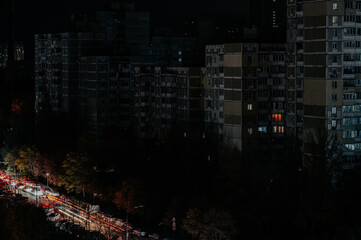 A darkened urban cityscape at night with minimal lights visible in apartment buildings and street traffic. The scene evokes a sense of blackout or power outage © Höyka Studio