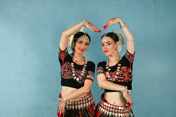Indian female dancers in beautiful costumes on a blue background in the studio in dance poses