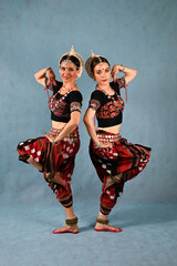 Indian female dancers in beautiful costumes on a blue background in the studio in dance poses