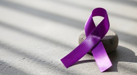 Purple ribbon on a stone with sunlight and shadow. World Cancer Day theme