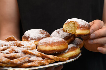 A man on a diet holding a tray of delicious jam packets and cookies sprinkled with powdered sugar.