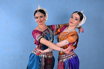 Indian female dancers in beautiful costumes on a blue background in the studio in dance poses