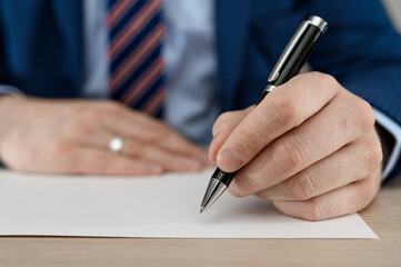 An office worker writes notes on a piece of paper in a notebook.