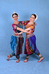 Fototapeta premium Indian female dancers in beautiful costumes on a blue background in the studio in dance poses
