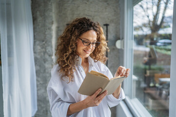 Woman with eyeglasses reading book enjoying quiet hobby time