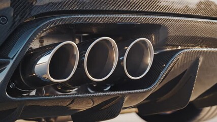 Close-up of a high-performance car's triple exhaust pipes, showcasing its powerful and sporty design elements