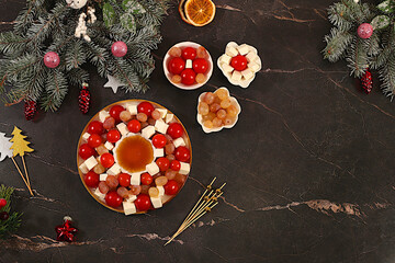 Christmas and New Year's dishes, traditional holiday salad with feta cheese, tomatoes, grapes, olives and honey with fir branches and decorations, dish decoration idea, menu template