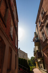 Obraz premium Historic Tenement Houses in Gniezno, Poland - Charming Street Scene Ideal for Travel Agencies, City Guides, and Tourism Campaigns. Narrow Street with Old Brick Buildings and Warm Afternoon Sunligh