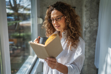Woman enjoying morning coffee and reading book at home