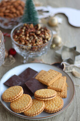 Various Christmas decorations, cookies, chocolate and nuts on wooden background. Selective focus.