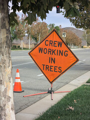 Crew working in trees warning sign on roadway