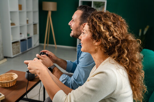 Smiling couple enjoying competitive video game at home