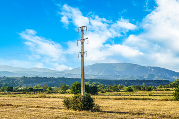 Concrete pillar reinforced with high-voltage cables against a clear blue sky. Transmission of...