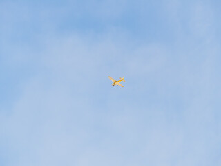 Small ultralight airplane with overhead wing and single propeller flying in sunset sky.
