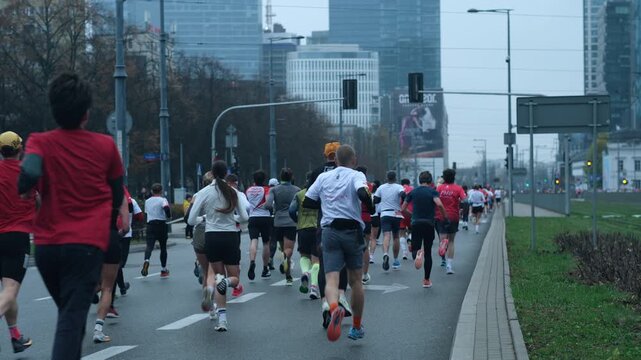 Back view of crowd running on city street during marathon