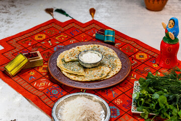 Traditional Azerbaijani qutab assortment served on a decorated table. Various flatbreads filled with pumpkin, meat, herbs, and cheese, presented with national ornaments and authentic tableware.