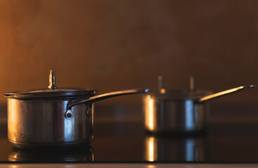 Close up of two steel pots on induction hob, interior