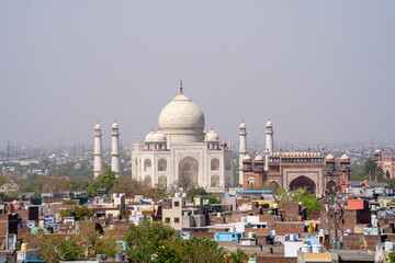Obraz premium Agra cityscape with the Taj Mahal in white marble standing out on the horizon surrounded by small brick houses