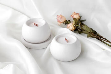 Scented candles with wooden wick in plaster candlestick, twisted white fabric on background,...