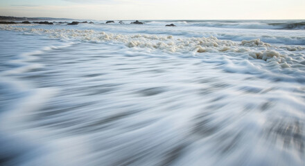 Gentle Ocean Waves Wash Ashore Creating Foamy Patterns on the Sand