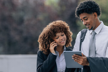 businessman with tablet and businesswoman with mobile phone talking and sharing