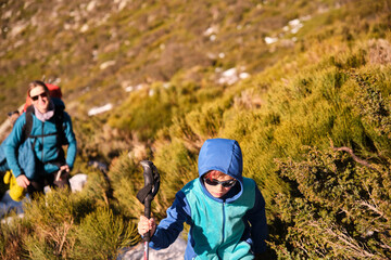 Mother and her son wearing sunglasses walking in the mountains on a sunny day