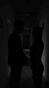 Silent couple fighting in the dark hallway, psychological tension and emotional distance