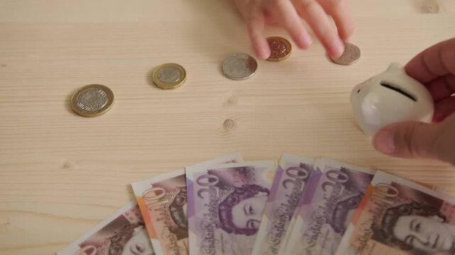 young girl's hands carefully count and deposit coins into piggy bank, English pence and pounds, Financial literacy for kids, savings mindset, financial management, big goals