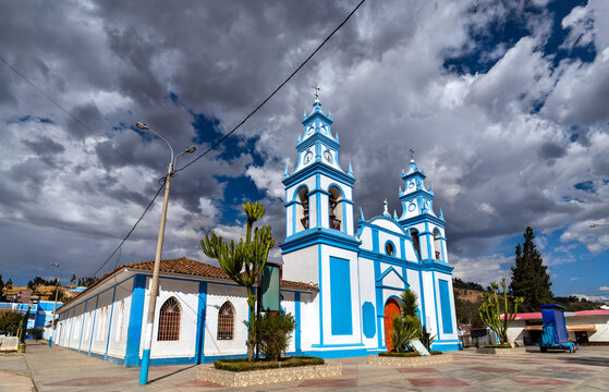 Immaculate Conception Church in Concepcion, Junin, Peru. The white and blue colonial-style building stands under a dramatic cloudy sky