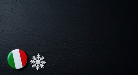 A vibrant round Italian flag badge is placed beside a delicate white snowflake decoration on a dark, rough slate background, providing generous copy space.