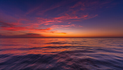 Fototapeta premium Ocean waves reflecting vibrant sunset colors under a twilight sky.