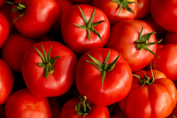 Organic red tomatoes for sale at farmers market. Fresh tomatoes displayed at local market stall. Heap of fresh tomatoes at outdoor vegetable market.