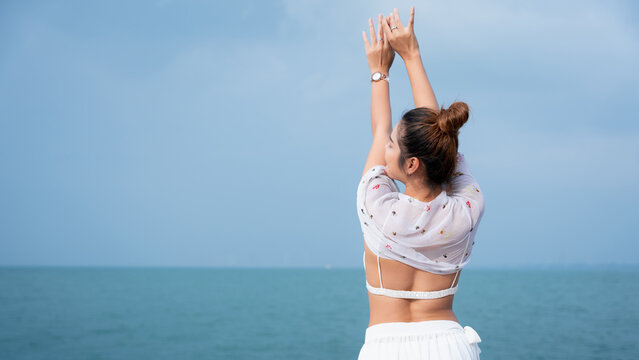 Beautiful woman relaxing on yacht with blue sea background, wearing white bikini and floral shawl under sunlight. Summer vacation lifestyle, freedom, and luxury travel concept.