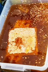 Texture of honeycombs close up. Yellow wax honeycombs with honey in plastic containers. Sale of homemade honey at the fair