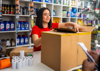 Woman employee packing a cardboard box for shipping orders in an auto parts retail store