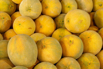 Fresh melons displayed on market stall. Heap of sweet melons at farmers market. Seasonal melons displayed at street market.