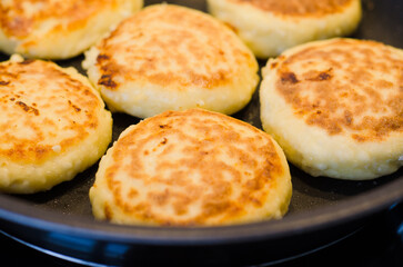 Hot golden cottage cheese pancakes syrniki freshly cooked on a frying pan