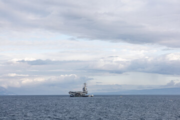 Naval Aircraft Carrier At Sea With Small Support Vessel Under Cloudy Sky