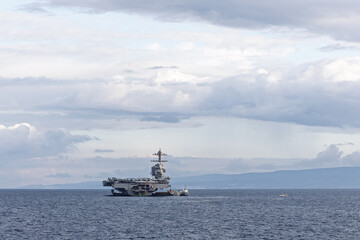 Naval Aircraft Carrier At Sea With Small Support Vessel Under Cloudy Sky