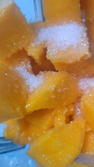 Close up shot of mango pieces with sugar sprinkled on top in a clear container ready to be eaten