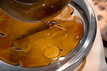 Pouring hot caramel on metal tray for homemade candies