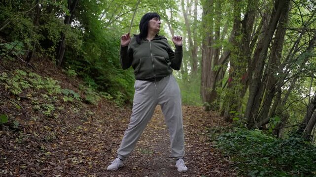 calm elderly woman performing mindful breathing, relaxed female engaging in grounding breathing exercises outdoors, woman in casual attire practicing peaceful breathwork beneath leafy cover