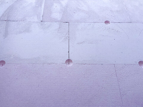 Insulation boards of extruded polystyrene foam (XPS) with anchor holes, showing thermal facade installation and construction texture for energy efficiency and modern architecture.