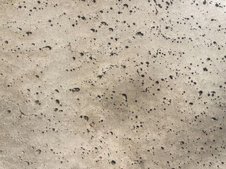 Heavily pitted concrete surface texture with dark spots, showcasing industrial grunge material for abstract backgrounds, urban design concepts, and rough architectural cladding