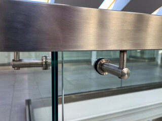 Close-up of a modern stainless steel railing corner on a glass balustrade, emphasizing seamless metalwork, contemporary design, and polished architectural details for commercial and luxury interiors.