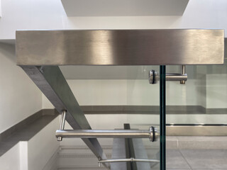 Close-up of a modern stainless steel railing corner on a glass balustrade, emphasizing seamless metalwork, contemporary design, and polished architectural details for commercial and luxury interiors.